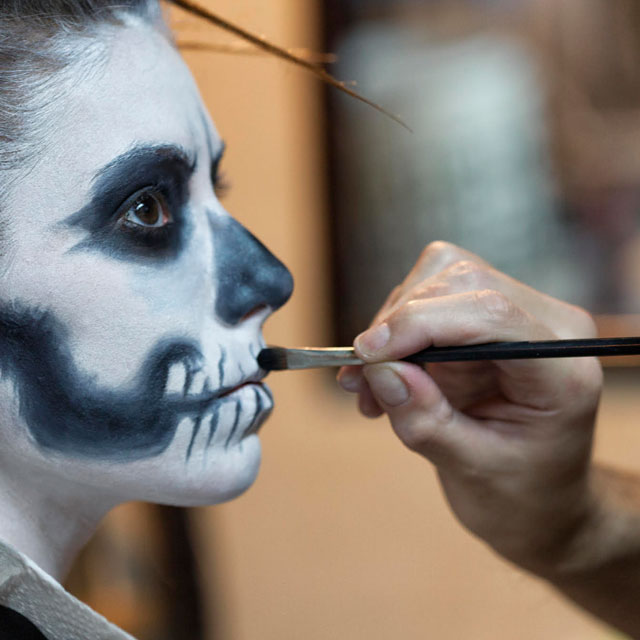 person getting their face painted as a skull