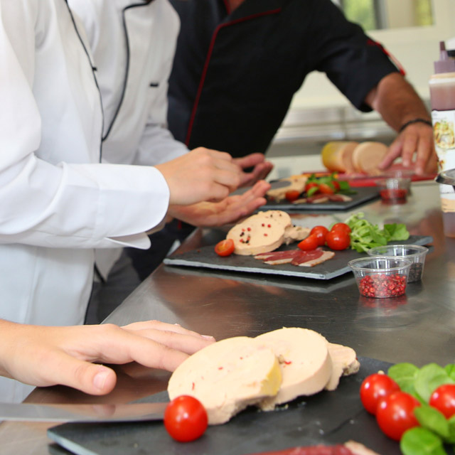 three sets of hands preparing food in a commercial kitchen