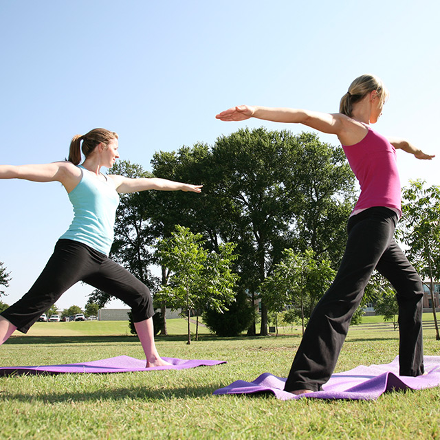 two women doing yoga in a park