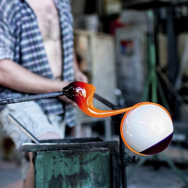 a person shaping molten glass