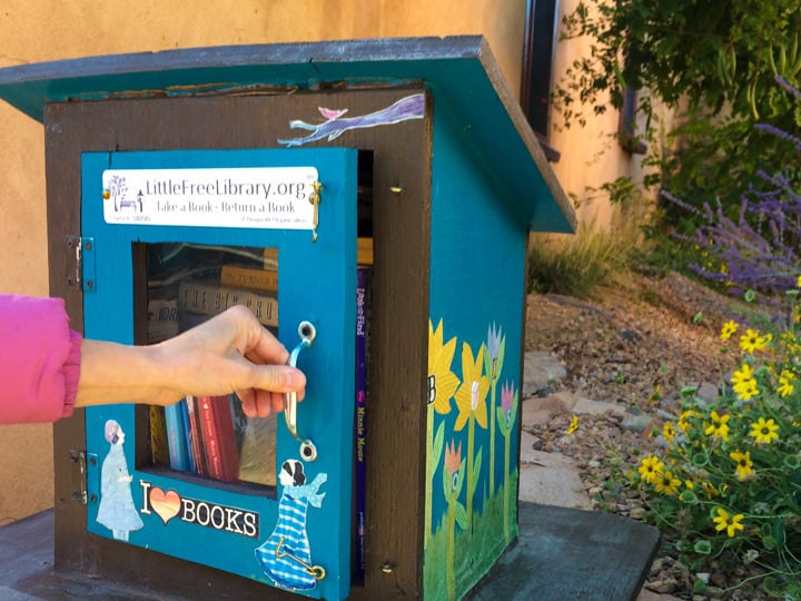 hand opening a little free library box