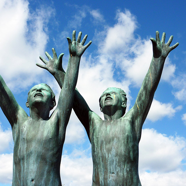 bronze metal statue of two men with their hands in the air