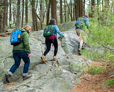 three people hiking on rocky ground in the woods