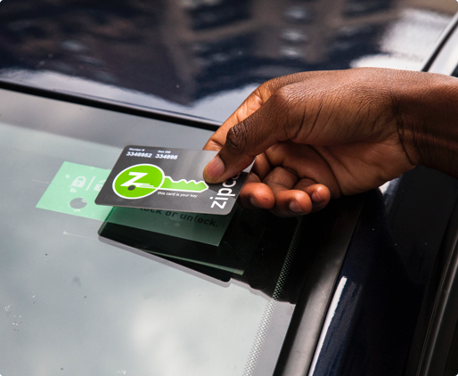 Hand holding zipcard over card reader to unlock car