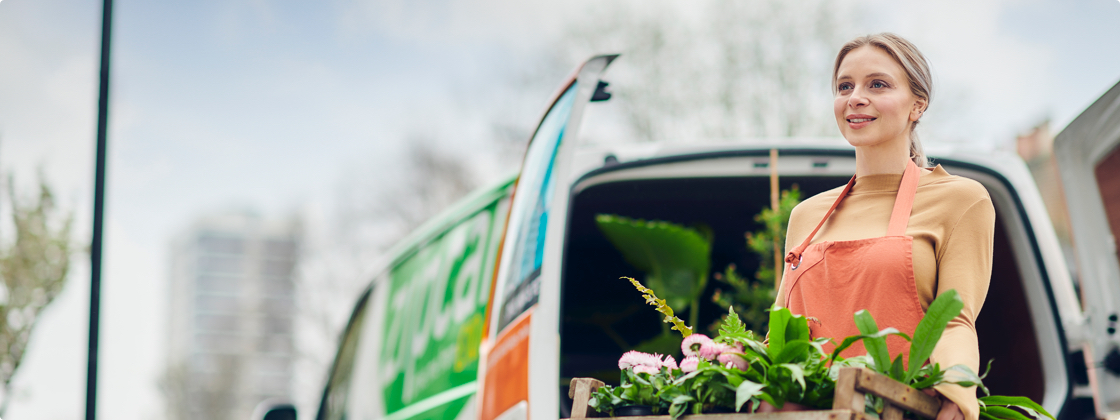 woman standing next to a Zipvan holding plants