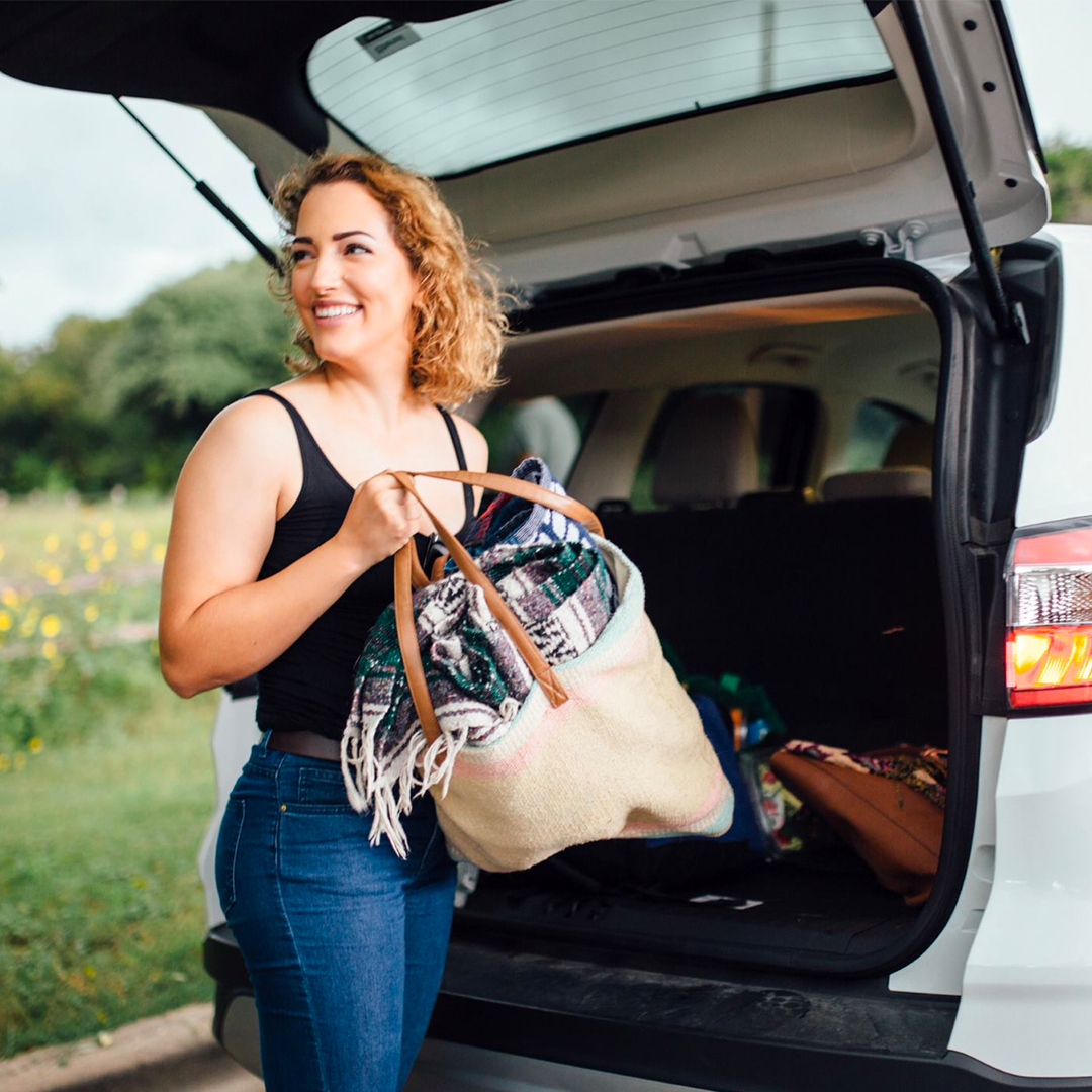 Woman grabbing beach/picnic bag out of the back of her Zipcar