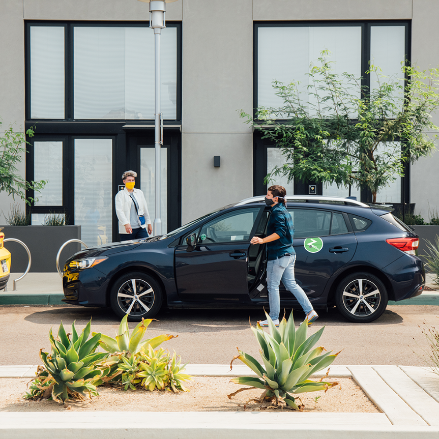 man with flannel shirt getting into dark blue hatchback with zipcar logo