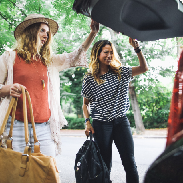 Two women looking in the trunk of an open SUV