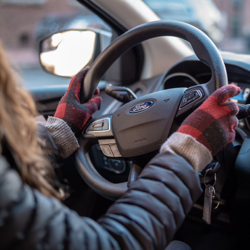 Gloved hands on a Ford vehicle steering wheel