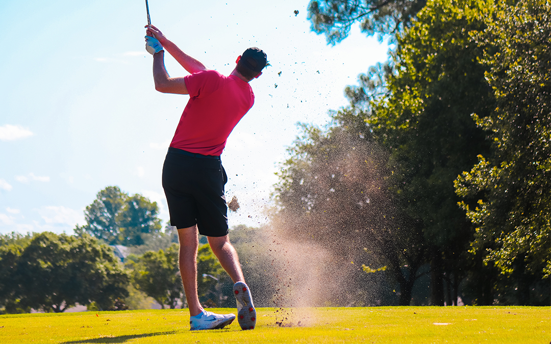 Man in a red shirt hitting a golf ball on the golf course