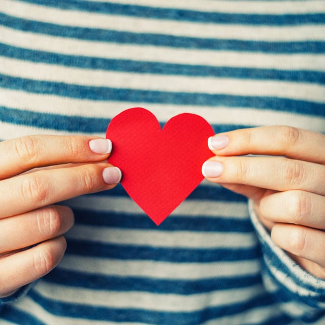 a person holding a small cutout heart with both hands