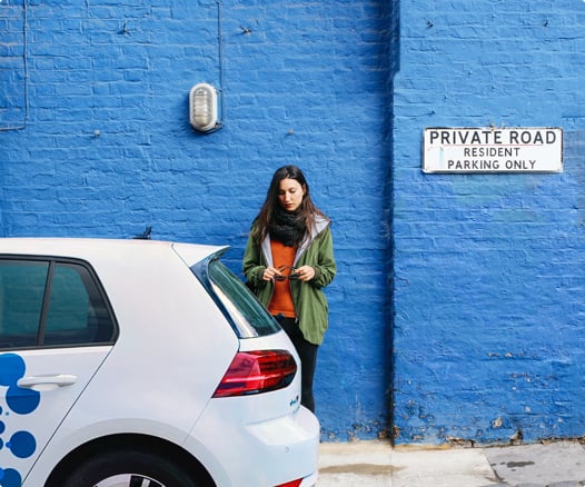 woman on cell phone with a Zipcar in the foreground